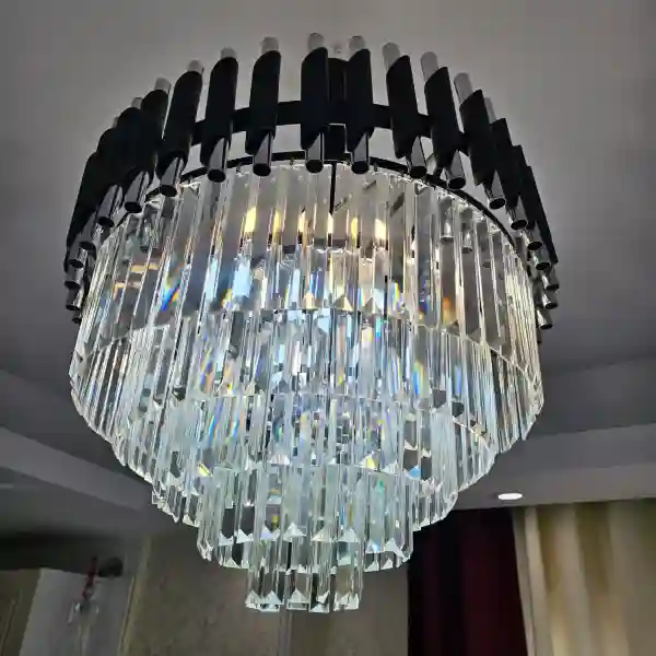 لوستر کریستالی مدل هونیا با بدنه مشکی و کریستال‌های کاردی شفاف در دکوراسیون پذیرایی