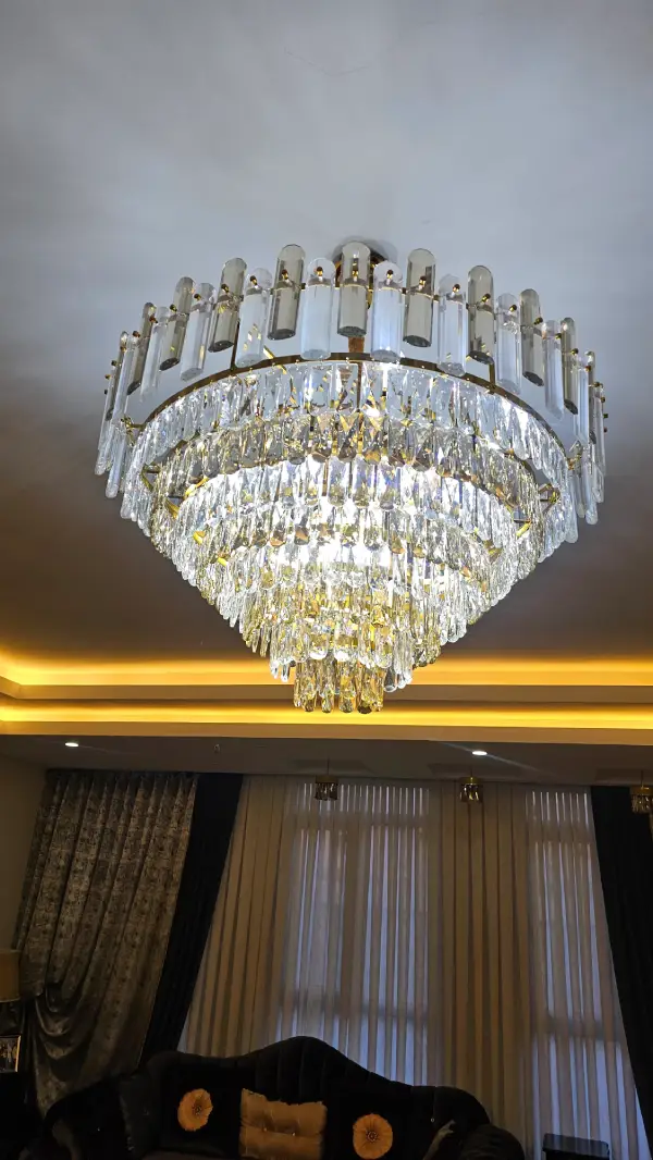 لوستر کریستالی طرح نورا آگرین لوستر با کریستال شامپاینی و شفاف نصب‌شده در سالن پذیرایی
